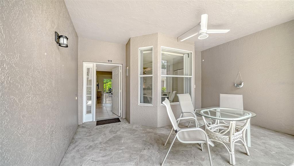 A covered patio features tiled flooring, a ceiling fan, and a small glass dining set — 8901 VERANDA WAY UNIT 111, SARASOTA, FL