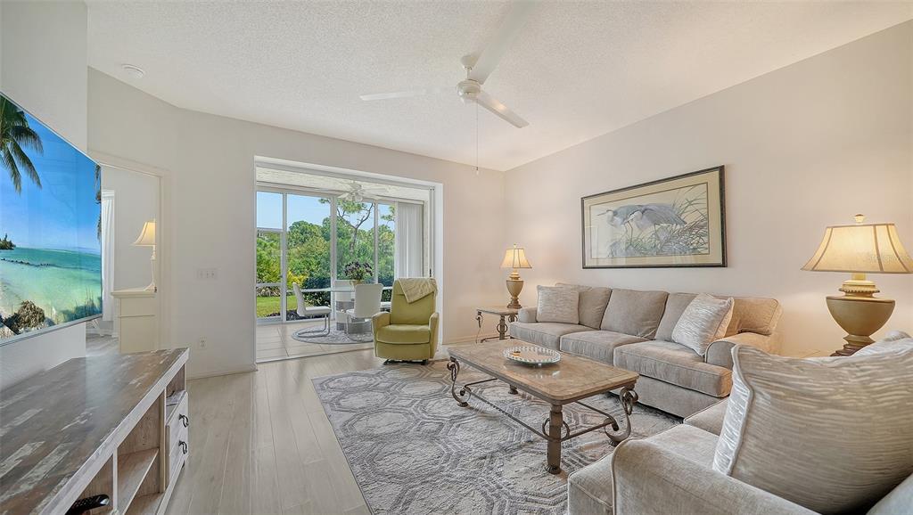 A living room with a beige sofa, patterned rug, and sliding glass doors to a patio — 8901 VERANDA WAY UNIT 111, SARASOTA, FL