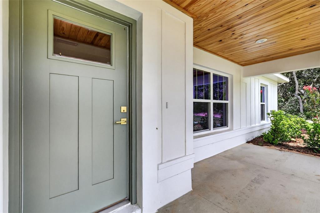 A light green front door opens onto a covered porch with a wood-paneled ceiling — 22 WALNUT COURSE, OCALA, FL