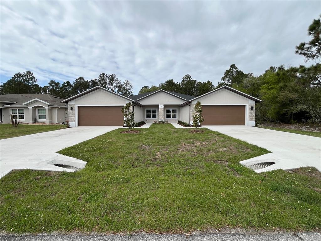 A duplex house with two garages and concrete driveways sits on a grassy lot — 35 FRENEAU LANE, PALM COAST, FL