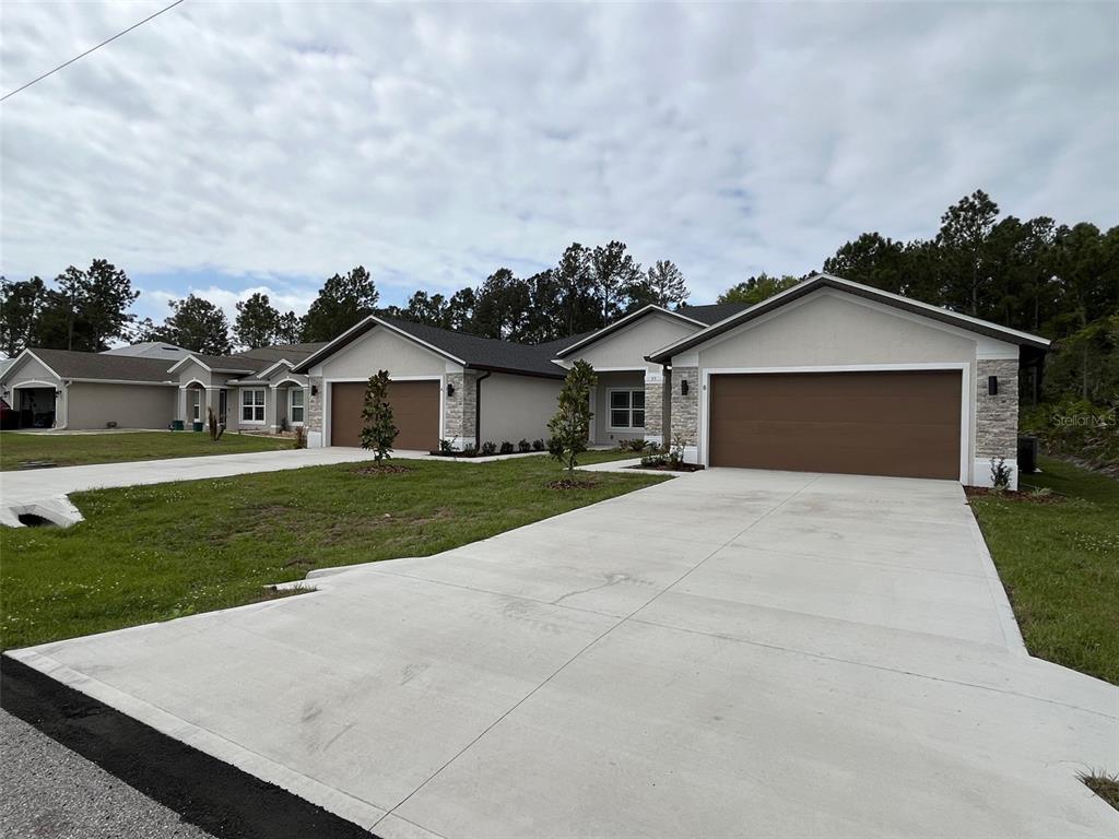 A view of two modern single-story suburban houses with concrete driveways and attached garages — 35 FRENEAU LANE, PALM COAST, FL