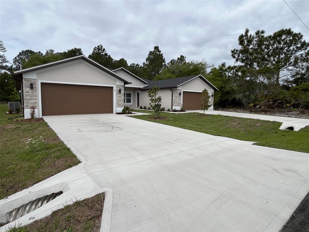 A modern duplex with two garages, stone accents, and a shared concrete driveway — 35 FRENEAU LANE, PALM COAST, FL