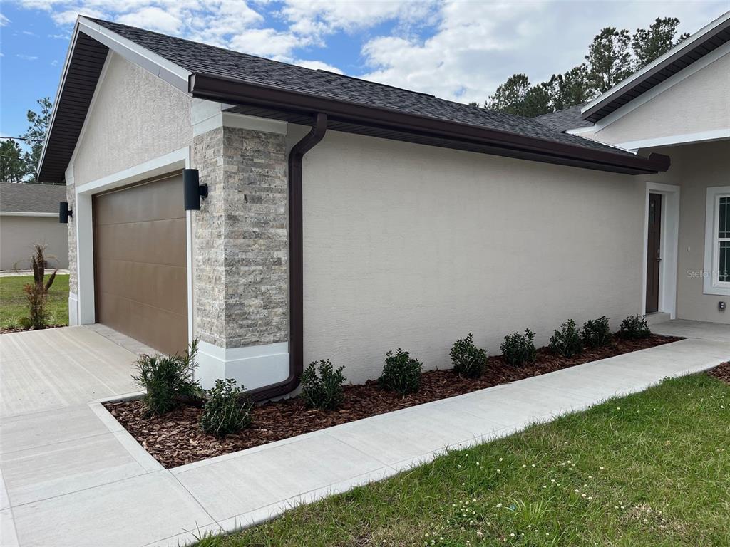 The exterior of a house features a garage, stone accents, and a concrete walkway — 35 FRENEAU LANE, PALM COAST, FL