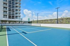 An outdoor tennis court with a blue surface sits beside a high-rise residential building — 6365 Collins Ave # 2201, Miami Beach FL 33141, MIAMI BEACH, FL