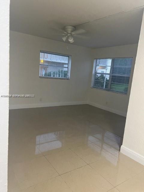 An empty room with light-colored tile flooring, a ceiling fan, and two windows with blinds — 4169 SW 67th Ave # 116A, Davie FL 33314, DAVIE, FL