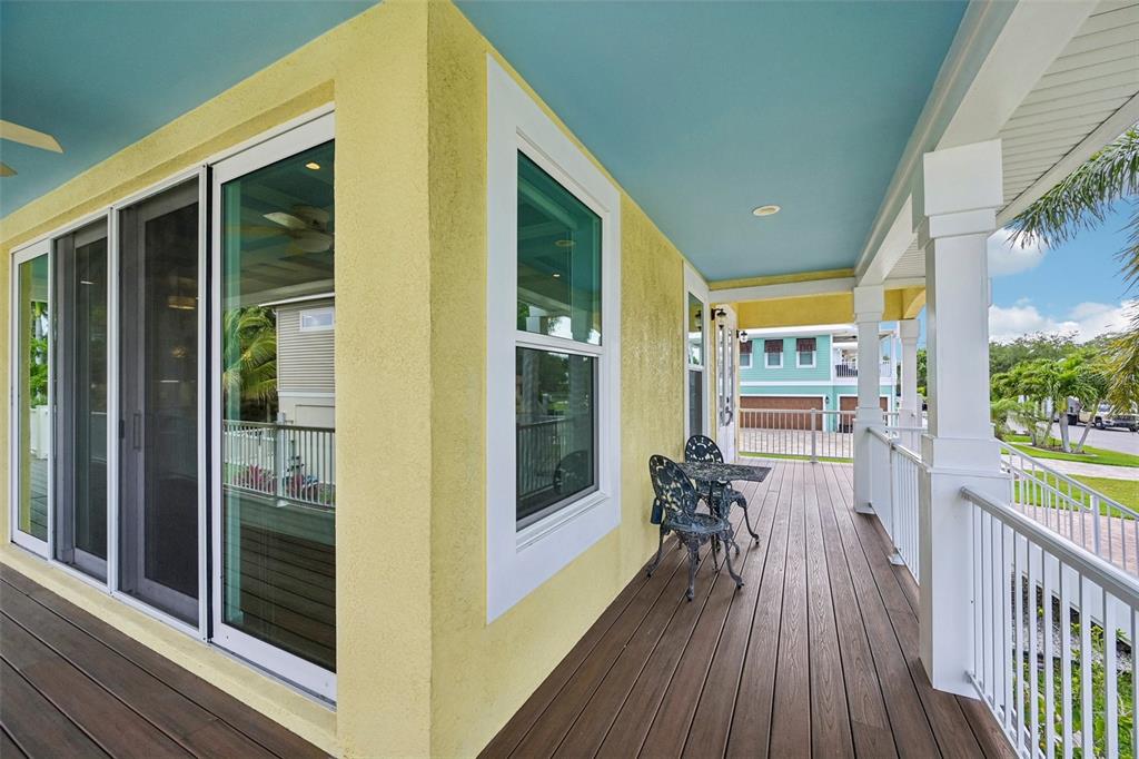 A yellow house exterior features a wooden deck, white railings, and a blue ceiling — 8174 17TH AVENUE W, BRADENTON, FL