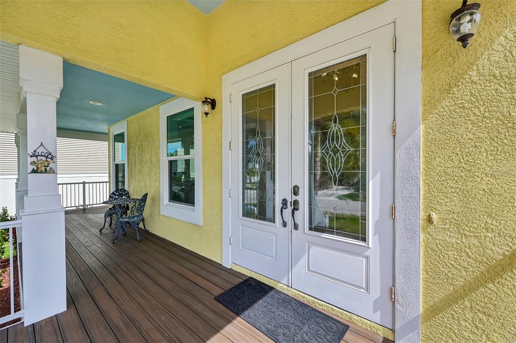 A yellow-walled front porch features a double door entry, a small table, and chairs — 8174 17TH AVENUE W, BRADENTON, FL