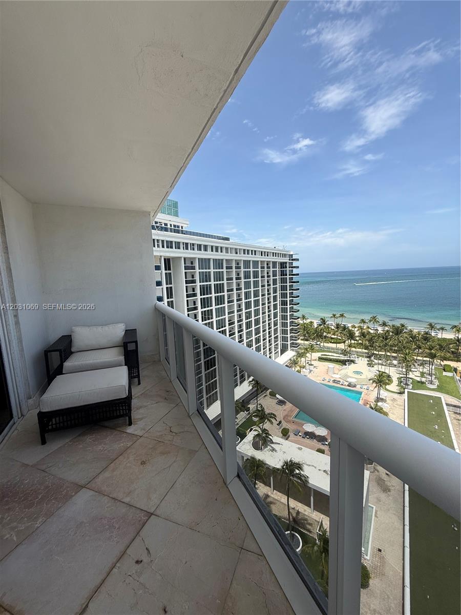 A balcony with a lounge chair overlooks a large resort complex and the ocean — 10275 Collins Ave # 1221, Bal Harbour FL 33154, BAL HARBOUR, FL