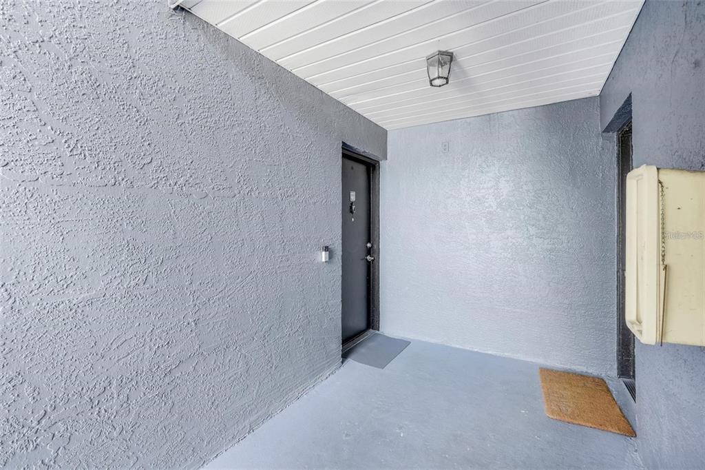 A covered entryway features gray textured walls, a dark door, and a light-colored ceiling — 4252 PERSHING POINTE PLACE UNIT 5, ORLANDO, FL
