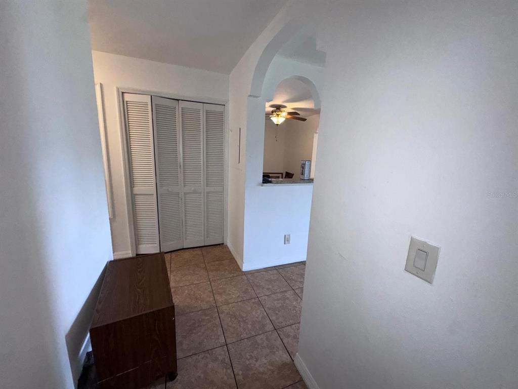 A tiled hallway features a louvered closet door, a wooden bench, and an arched opening — 4252 PERSHING POINTE PLACE UNIT 5, ORLANDO, FL