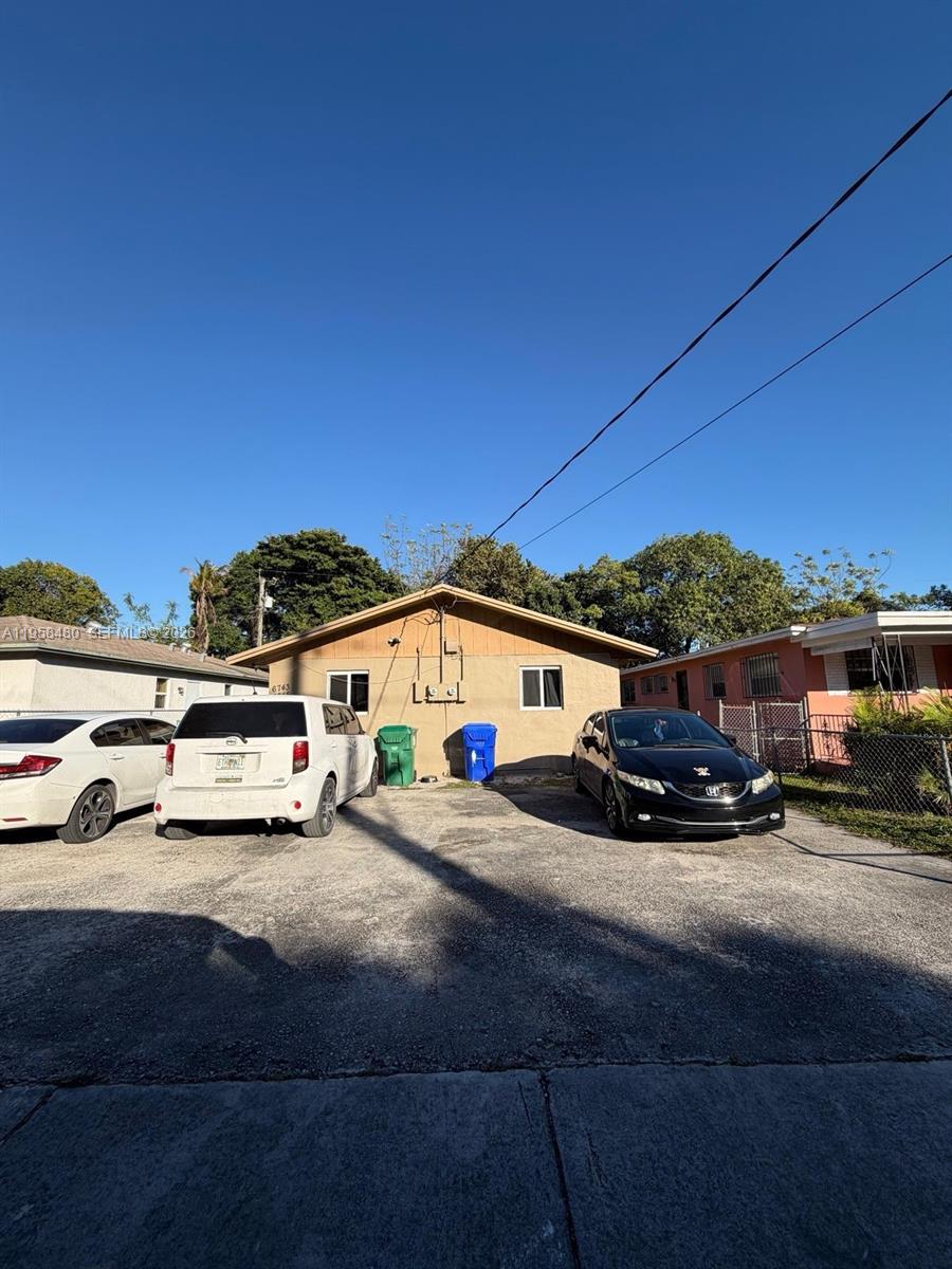A single-story house with a concrete driveway, two parked cars, and two trash bins — 6745 NW 4th Ct, Miami FL 33150, MIAMI, FL