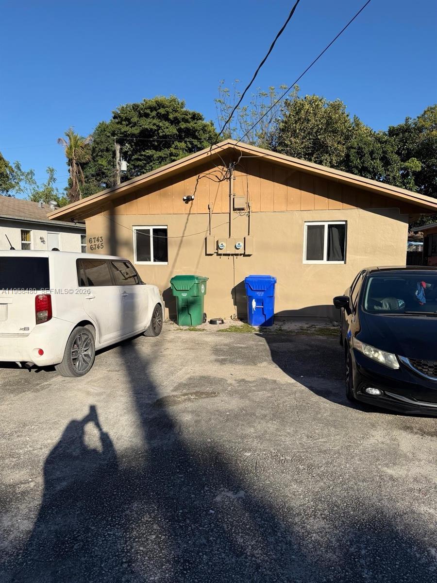 The exterior of a one-story building features a tan facade, two windows, and two trash bins — 6745 NW 4th Ct, Miami FL 33150, MIAMI, FL