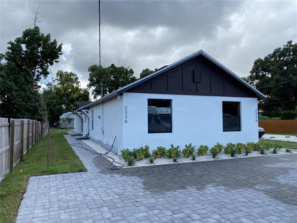 A white house with a dark gable and a paved driveway under a cloudy sky — 2336-2338 E JERSEY AVENUE, ORLANDO, FL