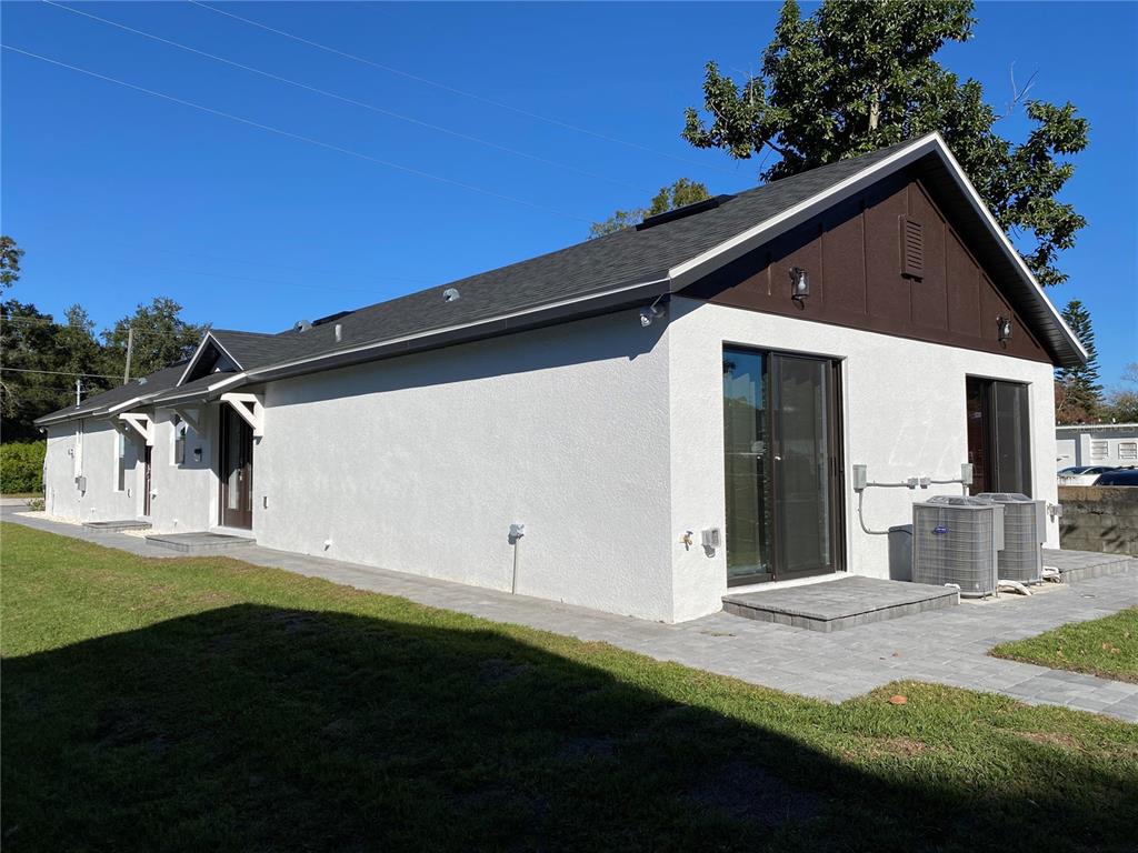 The exterior of a white stucco house features a dark gable roof and sliding doors — 2336-2338 E JERSEY AVENUE, ORLANDO, FL