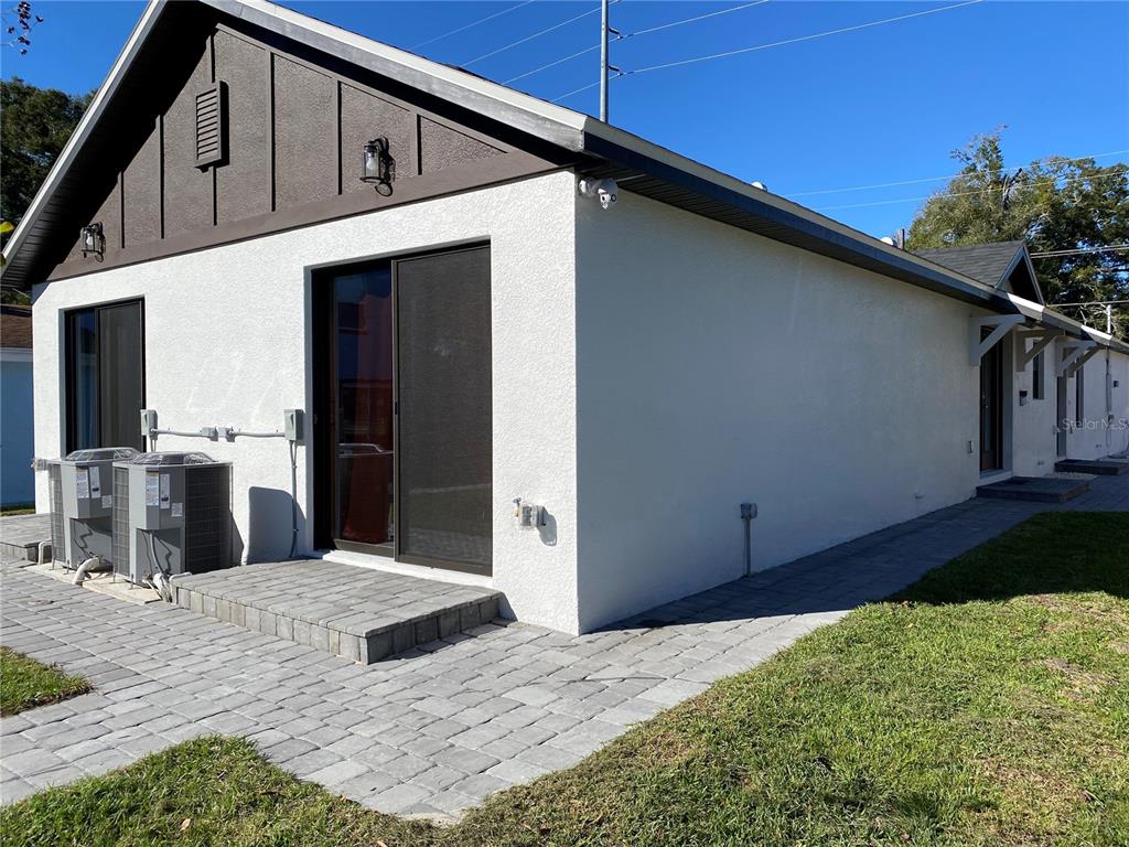 The exterior of a white stucco house features a paved patio and two air conditioning units — 2336-2338 E JERSEY AVENUE, ORLANDO, FL