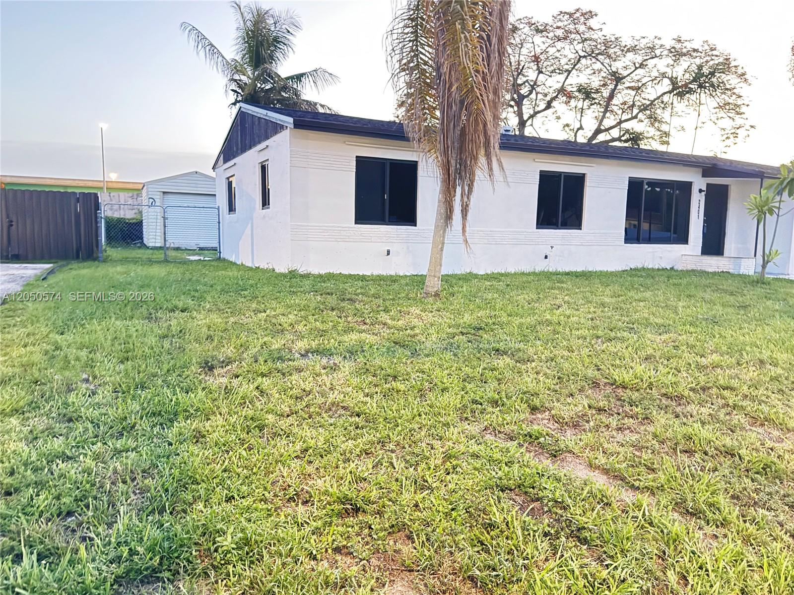 A white, single-story house with a dark roof and black window frames sits on grass — 2401 SW 50th Ter, Plantation FL 33317, PLANTATION, FL