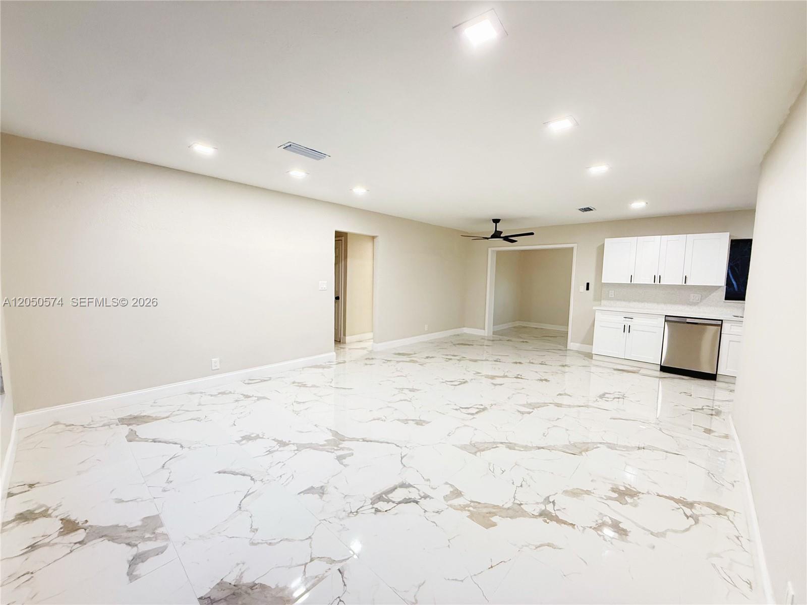 An open-concept room features white marble-patterned tile flooring and a kitchen with white cabinets — 2401 SW 50th Ter, Plantation FL 33317, PLANTATION, FL