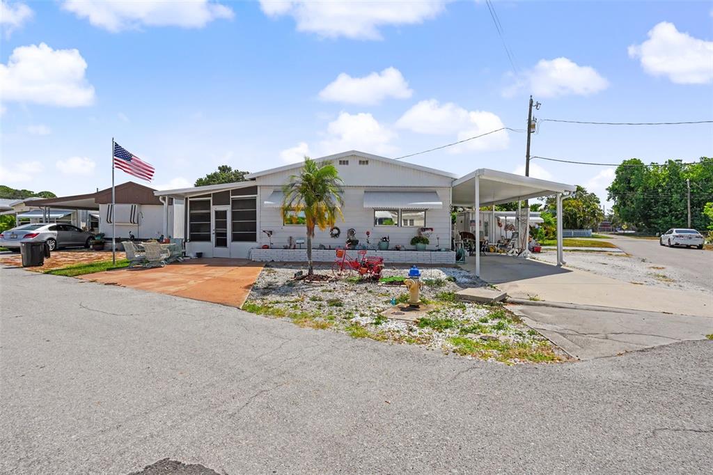 A single-story manufactured home features a carport, a front patio, and an American flag — 6523 KANSAS STREET, BRADENTON, FL