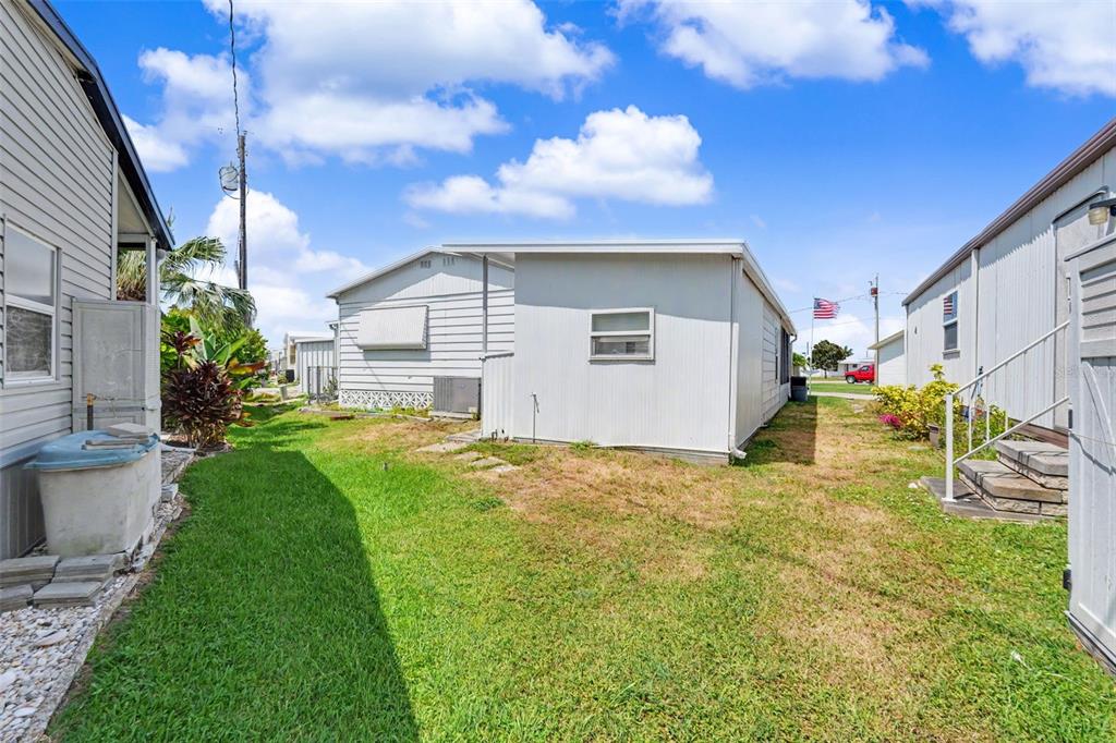 The exterior view shows a grassy yard between two mobile homes under a blue sky — 6523 KANSAS STREET, BRADENTON, FL