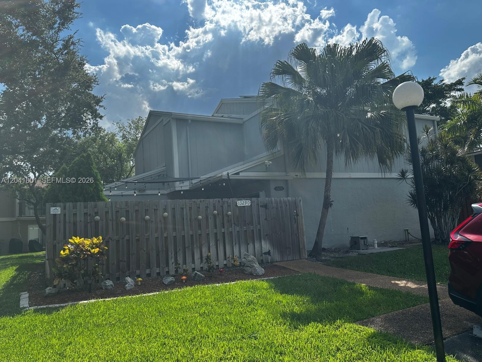 A two-story house exterior features a wooden fence, a palm tree, and a grassy lawn — 13290 NW 7th St, Plantation FL 33325, PLANTATION, FL
