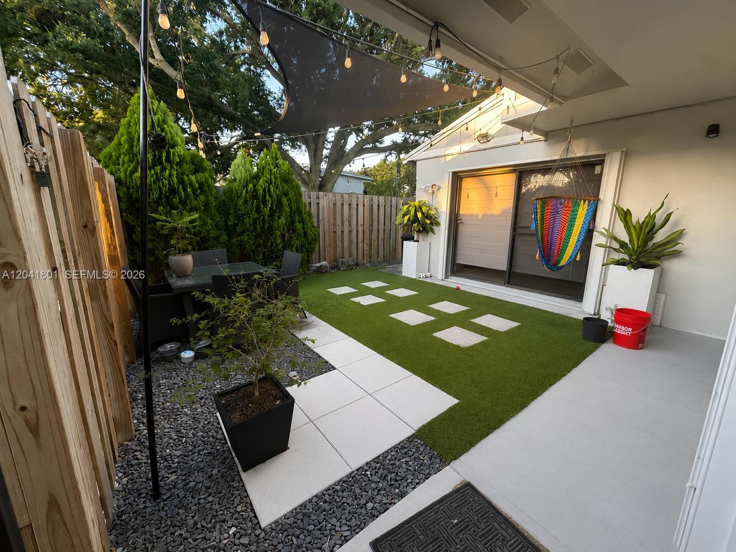 A backyard patio features artificial turf, stone pavers, a hammock, and string lights — 13290 NW 7th St, Plantation FL 33325, PLANTATION, FL