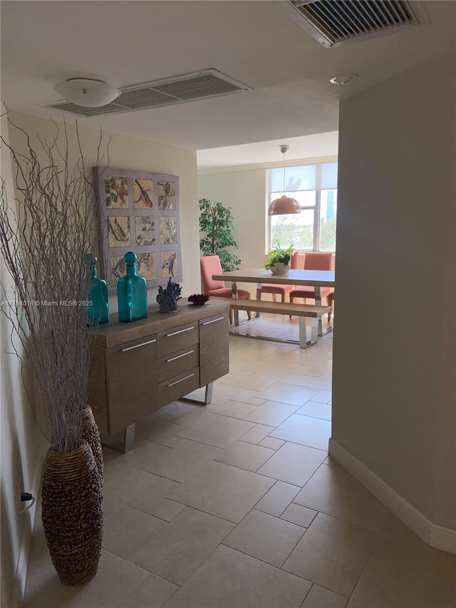 A hallway with a wooden sideboard leads into a dining area with a table and chairs — 3180 S Ocean Dr # 716, Hallandale Beach FL 33009, HALLANDALE BEACH, FL