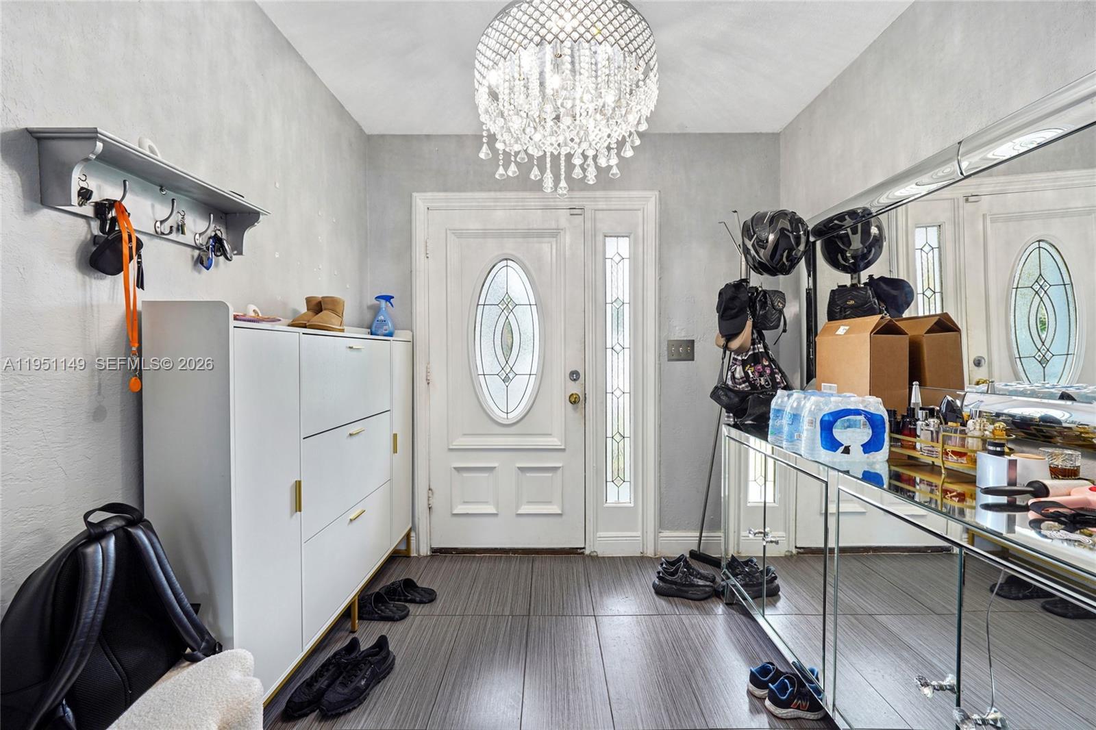 An entryway features a crystal chandelier, a white shoe cabinet, and a mirrored console table — 2534 Monroe St, Hollywood FL 33020, HOLLYWOOD, FL