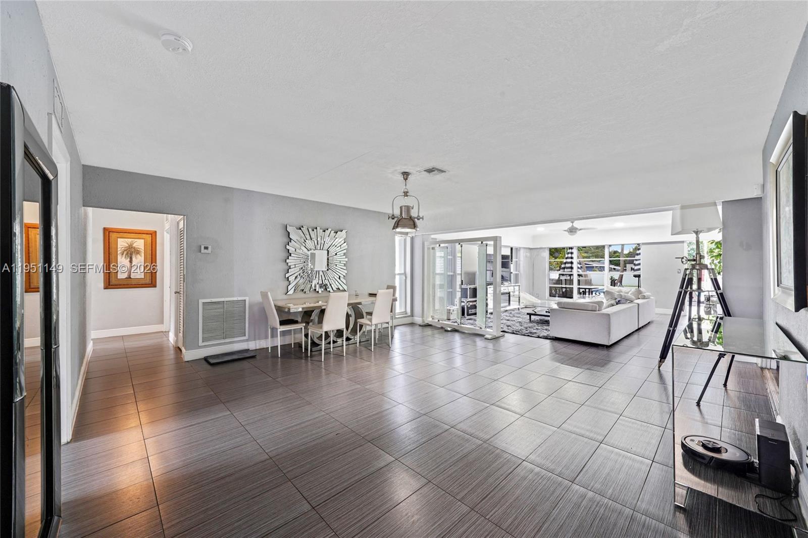 A spacious open-concept living and dining area features gray tile flooring and modern decor — 2534 Monroe St, Hollywood FL 33020, HOLLYWOOD, FL