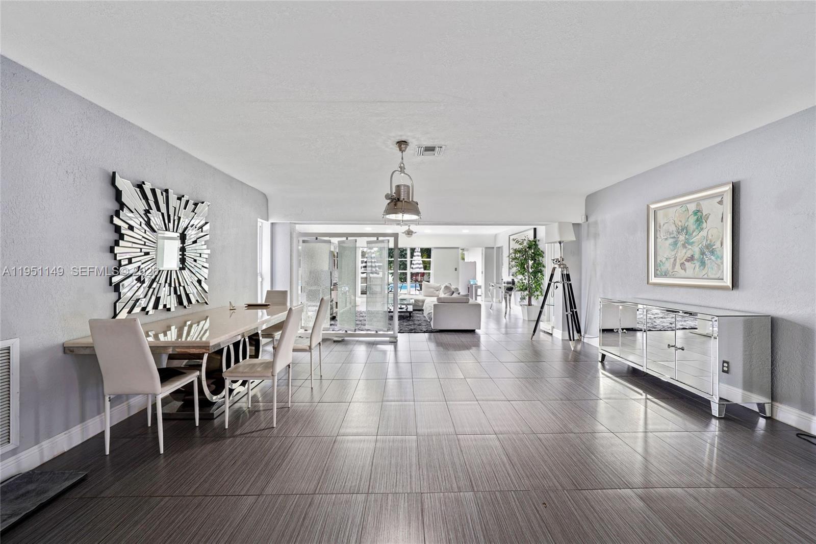 A dining area with a mirrored sideboard and table opens into a bright living space — 2534 Monroe St, Hollywood FL 33020, HOLLYWOOD, FL