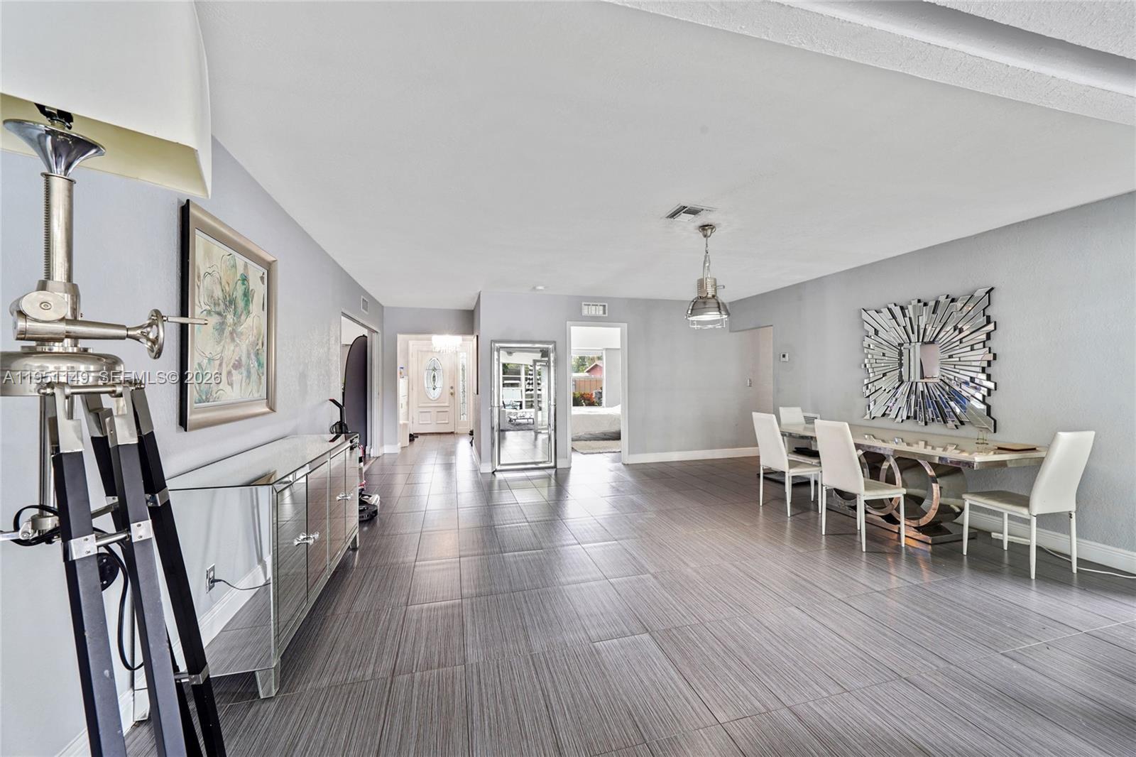 A dining area features gray tile floors, a mirrored sideboard, and a modern dining set — 2534 Monroe St, Hollywood FL 33020, HOLLYWOOD, FL