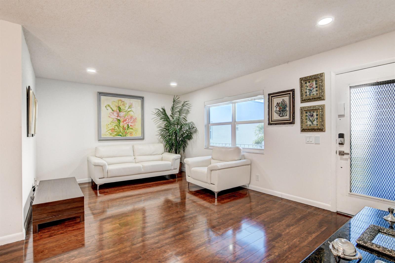A living room features white leather seating, a large floral painting, and dark hardwood floors — 42 Burgundy A, Delray Beach FL 33484, DELRAY BEACH, FL