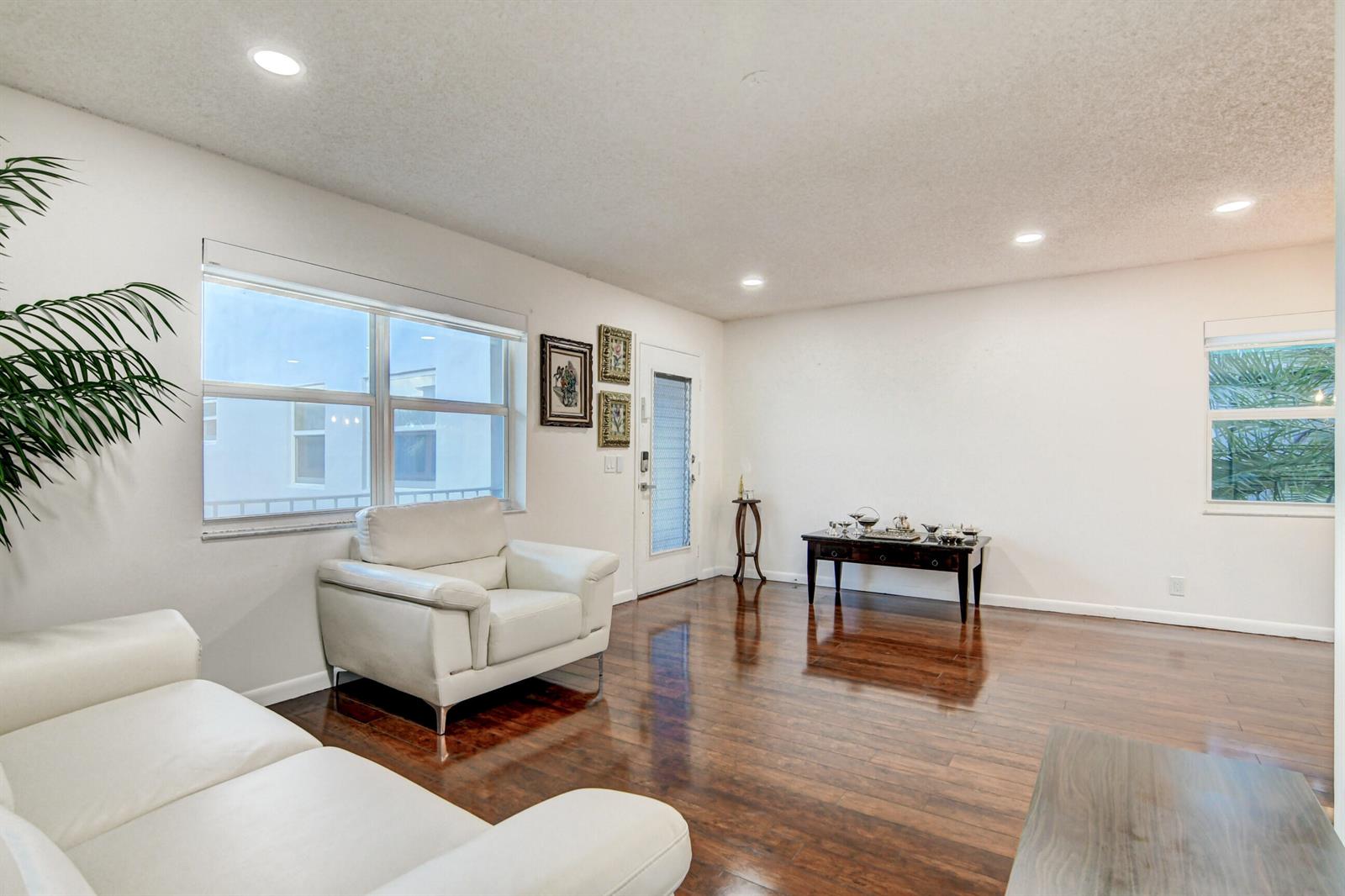 A living room with white walls, dark hardwood floors, white furniture, and a front door — 42 Burgundy A, Delray Beach FL 33484, DELRAY BEACH, FL