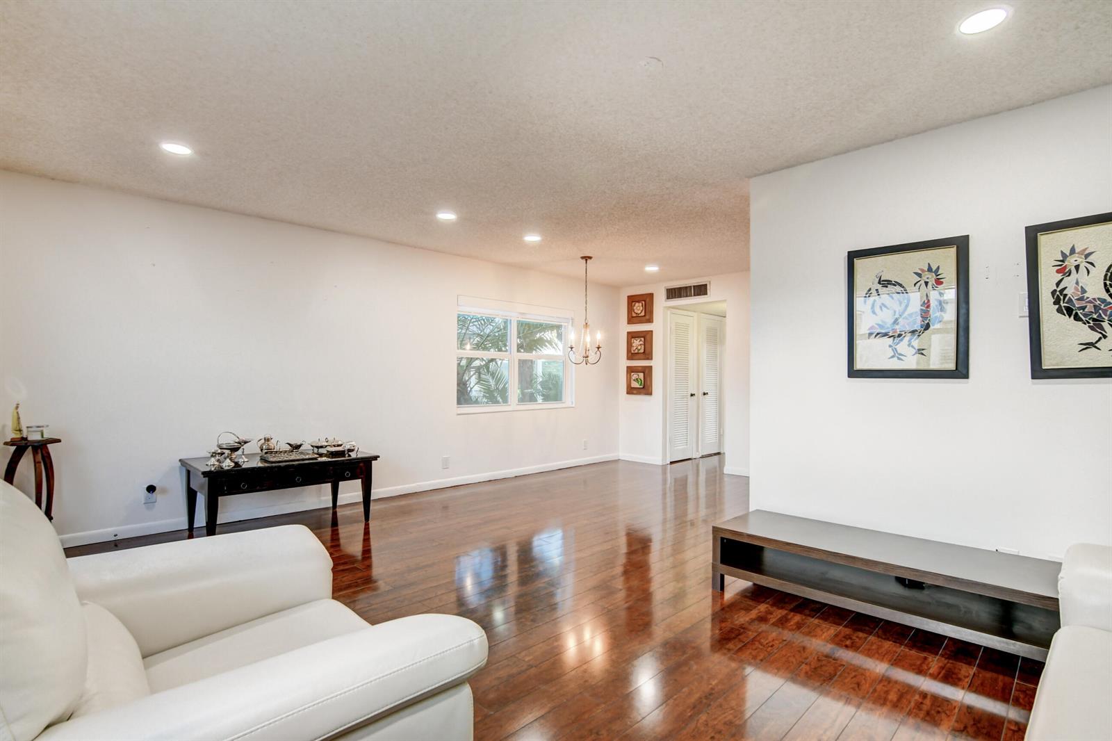 A living room features white walls, dark hardwood floors, recessed lighting, and a chandelier — 42 Burgundy A, Delray Beach FL 33484, DELRAY BEACH, FL