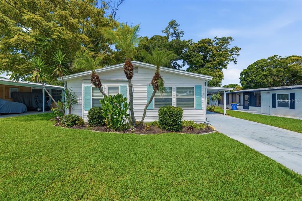 A single-story white mobile home with teal shutters and palm trees in the front yard — 304 PORTSIDE LANE, EDGEWATER, FL