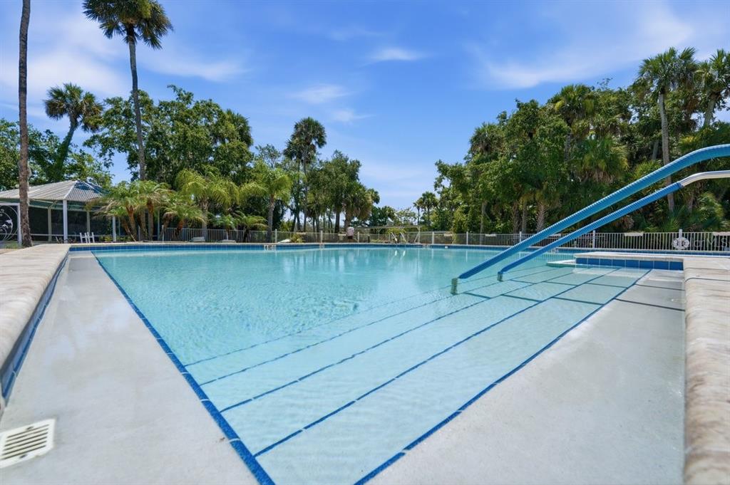 A large outdoor swimming pool with steps and a blue metal handrail — 304 PORTSIDE LANE, EDGEWATER, FL