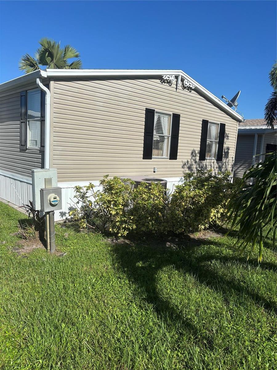 The exterior of a tan mobile home features vinyl siding, black shutters, and a central air unit — 5116 NW 4th Avenue, Deerfield Beach FL 33064, DEERFIELD BEACH, FL