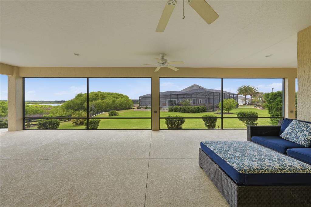 A covered, screened-in patio features a concrete floor, ceiling fans, and a view of landscaping — 1166 BLOUNT AVENUE, THE VILLAGES, FL