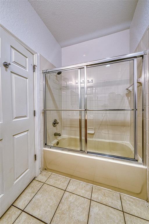 A bathroom features a beige bathtub with a sliding glass door and tiled walls — 2759 CORVETTE LANE, KISSIMMEE, FL