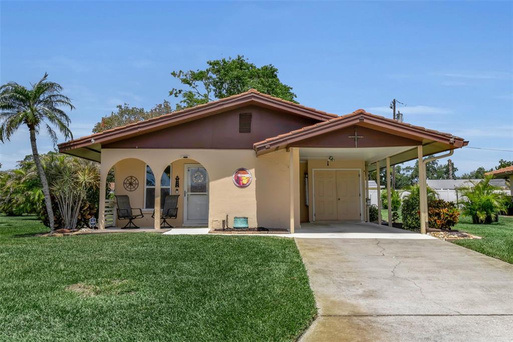 A single-story house with a tan exterior, brown roof, covered carport, and front porch — 3311 MERCER ROAD UNIT 3311, BRADENTON, FL
