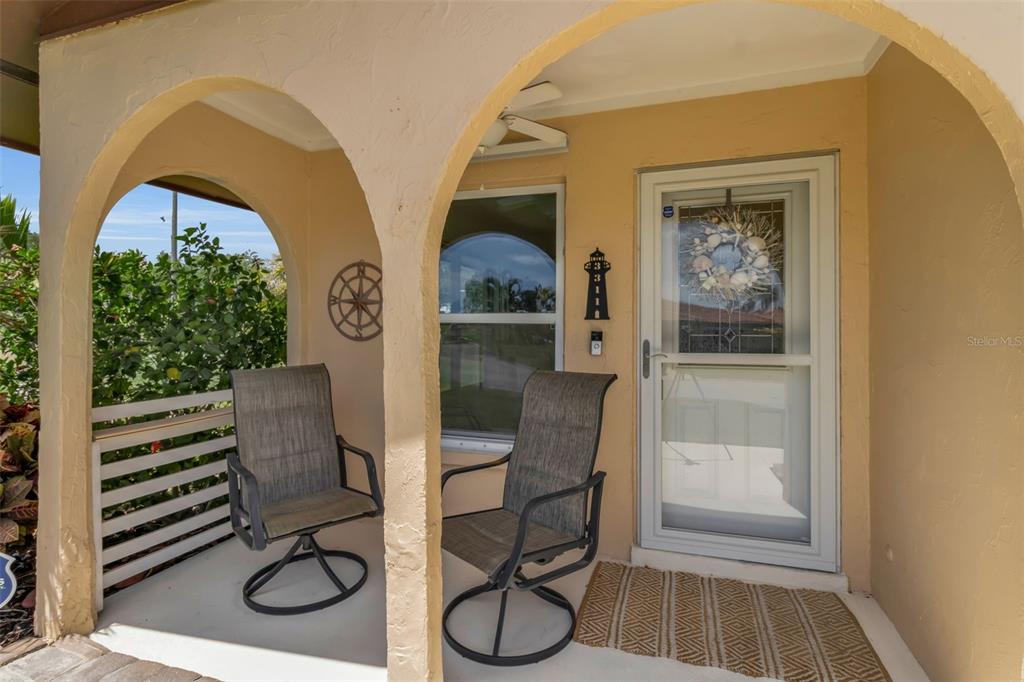 A covered front porch features two chairs, a storm door, and a lighthouse-shaped address plaque — 3311 MERCER ROAD UNIT 3311, BRADENTON, FL