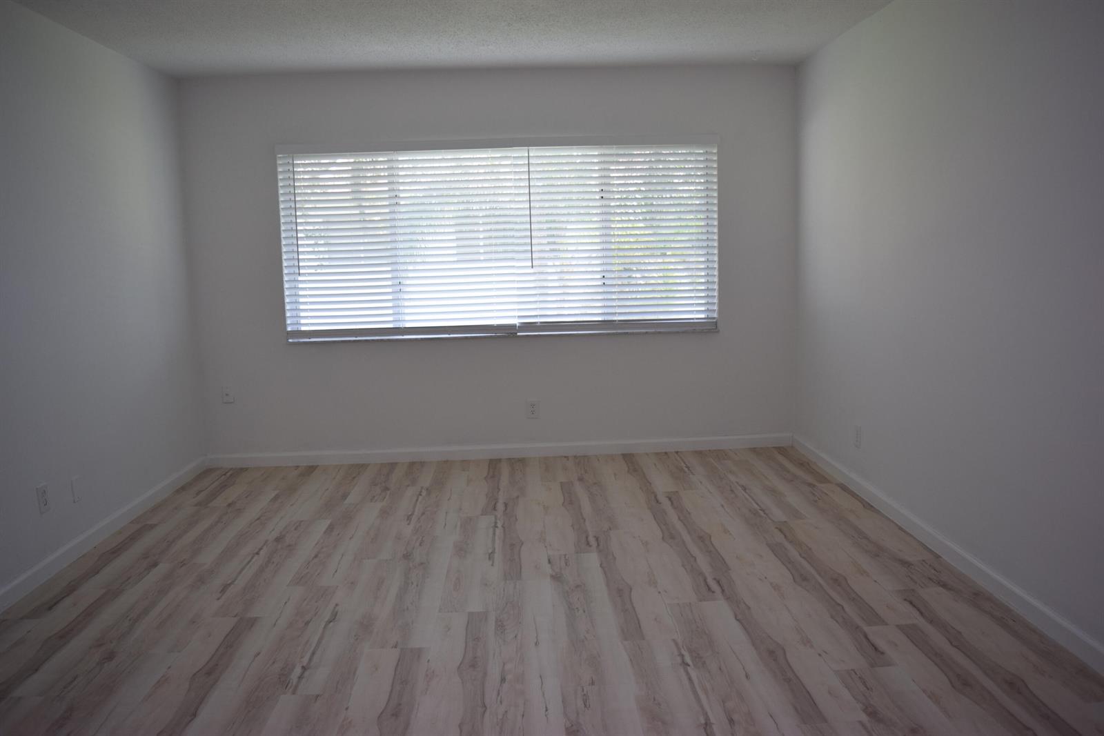 An empty room with white walls, light wood-look flooring, and a window with horizontal blinds — 151 SE 6th Avenue # 14, Pompano Beach FL 33060, POMPANO BEACH, FL