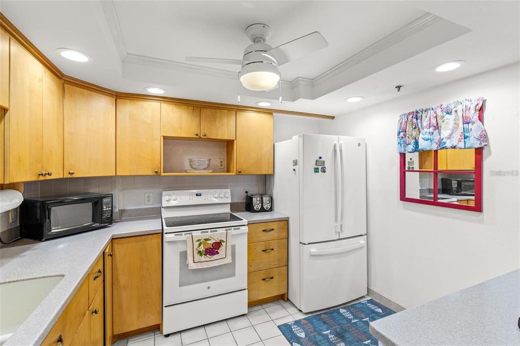 A kitchen with light wood cabinets, white appliances, and a ceiling fan — 1 KEY CAPRI UNIT 104-East, TREASURE ISLAND, FL