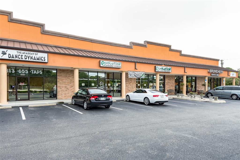 An exterior view of a single-story commercial strip mall with several businesses and parked cars — 4325 LYNX PAW TRAIL UNIT 4325, VALRICO, FL