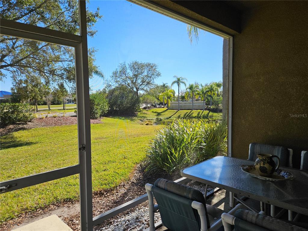 A screened-in patio overlooks a grassy yard, a small pond, and palm trees — 1161 JAMESON GREENS DRIVE, SUN CITY CENTER, FL