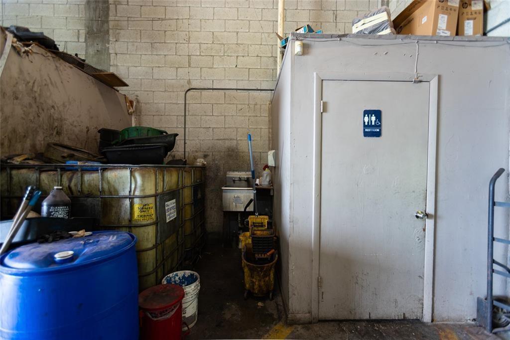 A utility area features a restroom door, a large plastic storage tank, and cleaning equipment — 669 NW 26th Street, Miami FL 33127, MIAMI, FL