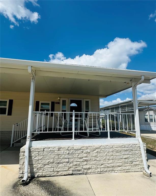 A mobile home features a covered front porch with a white railing and brick base — 917 ST GEORGE DRIVE, DAVENPORT, FL