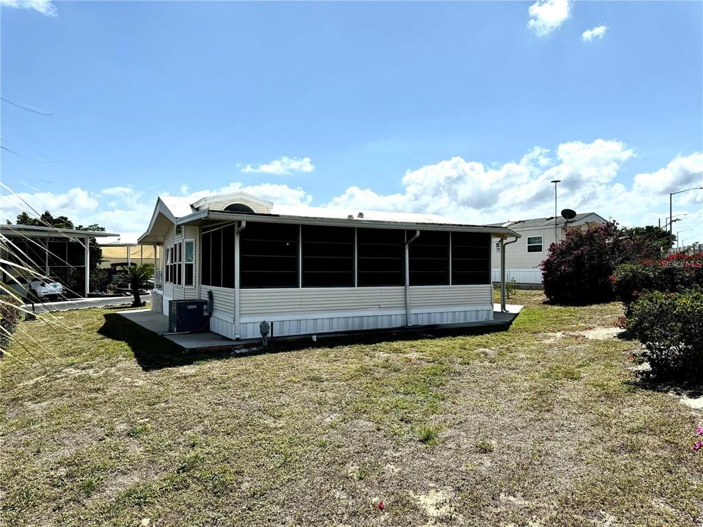 A beige mobile home features a large screened-in porch and a metal roof — 917 ST GEORGE DRIVE, DAVENPORT, FL