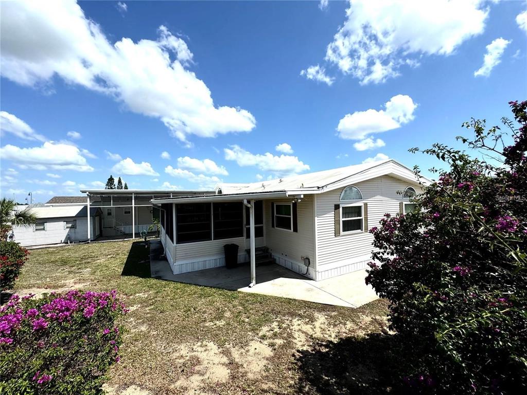 A single-story manufactured home with light siding, a screened-in porch, and a concrete patio — 917 ST GEORGE DRIVE, DAVENPORT, FL