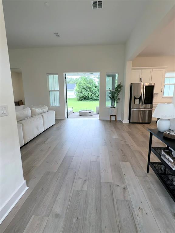 A bright living room features light wood flooring, a white sofa, and sliding glass doors — 310 W WASHINGTON AVENUE, LAKE HELEN, FL