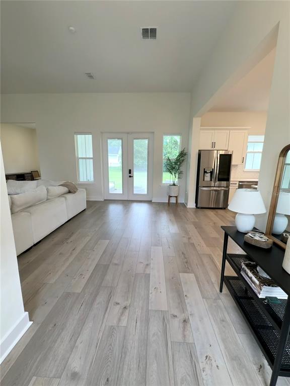 A bright living room features light wood flooring, a white sofa, and a kitchen beyond — 310 W WASHINGTON AVENUE, LAKE HELEN, FL